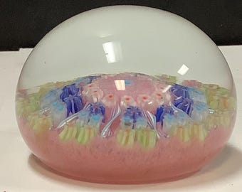May include: A clear glass paperweight with a pink, white, blue, and green floral design inside.