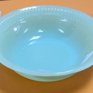 Puede incluir: Un tazón de vidrio azul claro con un borde festoneado. El tazón está hecho de vidrio opalino y tiene un acabado liso y brillante.