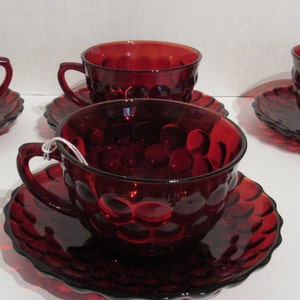 May include: Set of four red glass teacups and saucers with a bubbled texture. The cups and saucers are all the same size and shape.