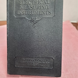 May include: Black leather-bound book titled "Electrical Measuring Instruments" by International Textbook Company, Scranton, PA.