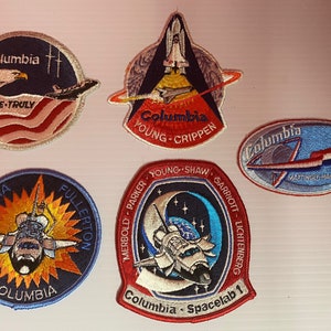以下が含まれることがあります： スペースシャトルコロンビアをフィーチャーした、異なるミッション名とクルーメンバーが刺繍された5つのパッチ。パッチは円形と楕円形で、青、赤、白のカラーリングです。