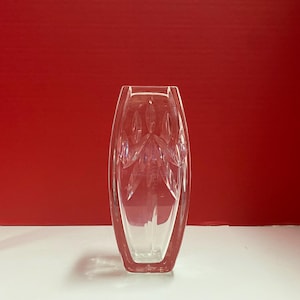 May include: A clear glass vase with a geometric pattern. The vase is tall and slender, with a rounded base and a flared top.