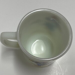 May include: White ceramic mug with a blue and yellow design. The mug has a handle and is empty.