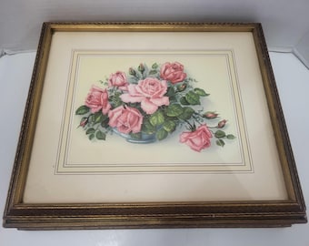 Könnte beinhalten: Ein gerahmter Druck eines Straußes rosa Rosen in einer blauen Vase. Die Rosen sind in einer Gruppe mit grünen Blättern und Stielen angeordnet. Der Druck ist auf einem weißen Hintergrund.