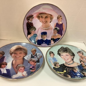 Op de afbeelding: Drie decoratieve keramische borden met afbeeldingen van prinses Diana. Elk bord heeft een andere achtergrondkleur en toont een collage van foto's van Diana op verschillende leeftijden en evenementen.