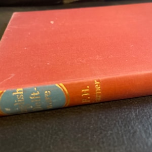 May include: A red hardcover book with a blue and gold spine. The title on the spine is "The Fish That Left the Sea" by F.H. Garner.