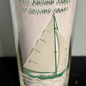 May include: Clear glass with a sailboat design. The glass features a white sailboat with green accents, sailing on white waves. The text "WELL KNOWN TYPES OF SAILING CRAFT" is printed in green.
