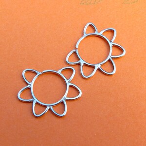 Könnte beinhalten: Zwei silberne Ohrringe in Blumenform. Die Ohrringe sind aus Metall und haben ein zartes, florales Design.