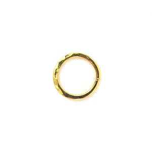 Puede incluir: Un aro de oreja de metal martillado de color dorado.