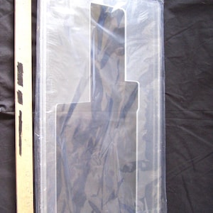May include: A clear plastic protective case for a record player. The case is rectangular in shape with a cutout for the record player's turntable.