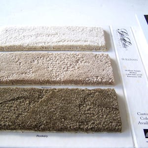 May include: Three carpet samples, one white, one beige, and one brown, with the text "Sullivan 24 Hour Sample Hotline 1-800-841-1720 Extension 190 Custom Color Available" printed on a white background.