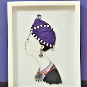 May include: A framed paper art piece depicting a woman's profile wearing a purple and white patterned head covering and a black and white patterned garment. The artwork is created using the quilling technique.