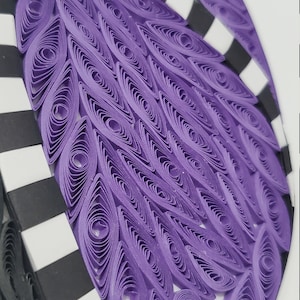 May include: Purple and black paper craft art with a geometric pattern. The purple section is made of rolled paper and the black and white section is made of stripes.