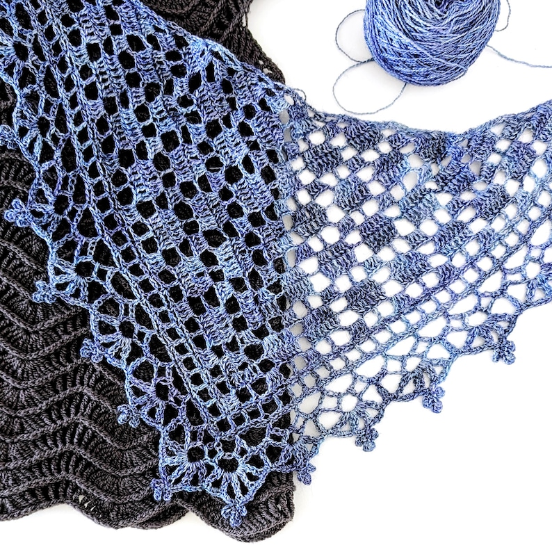 Puede incluir: Primer plano de tres chales de ganchillo en tonos azules y grises. Los chales presentan intrincados patrones calados y bordes decorativos. Una madeja de hilo azul se encuentra en la esquina superior derecha, lo que sugiere un proyecto artesanal.