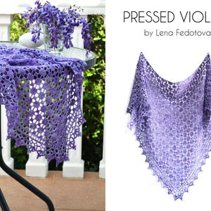 Puede incluir: Un chal hecho a mano, de tejido abierto, en tonos morados. El chal se muestra sobre una mesa y sobre un fondo blanco. El texto "PRESSED VIOLETS" y el nombre del artista son visibles.