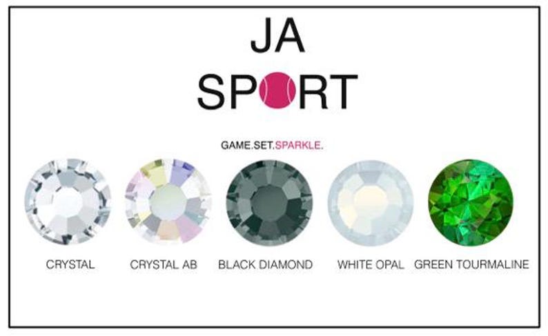 May include: A close-up of five different colored rhinestones. The rhinestones are labeled "Crystal", "Crystal AB", "Black Diamond", "White Opal", and "Green Tourmaline". The text "JA SPORT GAME.SET.SPARKLE." is above the rhinestones.