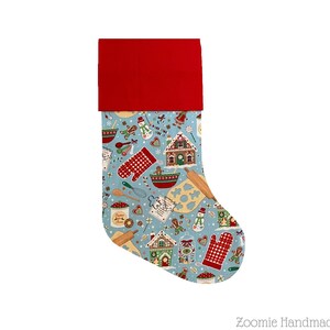 May include: A blue Christmas stocking with a red cuff. The stocking is decorated with a gingerbread house, gingerbread men, and other baking-themed designs.