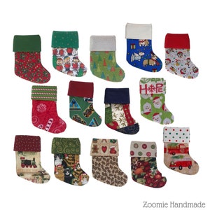 May include: A collection of 14 miniature Christmas stockings in various colors and patterns, including red, green, blue, and white. The stockings feature a variety of holiday designs, such as candy canes, snowflakes, and Santa Claus.