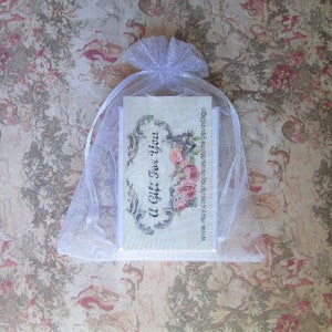 May include: A white organza gift bag tied with a ribbon, containing a card with the text "A Gift For You" and a floral design. The background features a vintage floral pattern.
