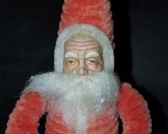 May include: A vintage Santa Claus figurine made of red velvet and white fur. He is holding a candy cane and wearing a black belt.