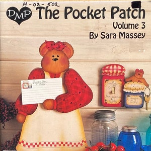 May include: The Pocket Patch Volume 3 by Sara Massey. The cover features a wooden bear holding a recipe card, with decorative jars and a bowl of cherries. The color palette includes red, brown, and cream.