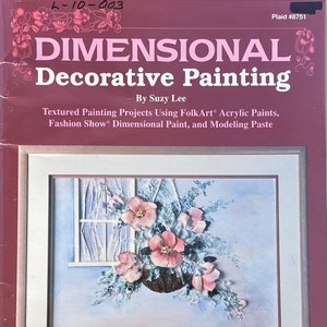 May include: A book cover with a pink and white floral painting in a frame. The title of the book is "Dimensional Decorative Painting" by Suzy Lee. The book cover is red with a plaid pattern in the bottom right corner.