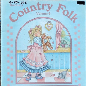 May include: A book cover with a light blue background and the title "Country Folk" in pink and brown lettering. The book is volume 6 and features an illustration of a girl holding a teddy bear. The text on the cover reads "There's a rip and a tear in my teddy bear... Love pours from him everywhere!" and "Includes Step-By-Step Embossing Instructions and Color Worksheet by Darcie Hunter."