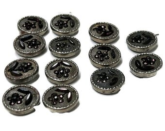 May include: Twelve silver-toned buttons with black and pink floral designs. The buttons are round and have a raised edge.
