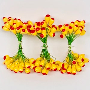 May include: Three bunches of yellow berry sprigs with red tips. Each bunch is tied together with a green wire.