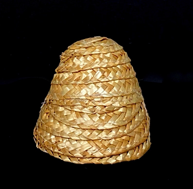 Pu&ograve; includere: Un cappello di paglia intrecciata a forma conica. Il cappello &egrave; realizzato in paglia marrone chiaro, fittamente intrecciata, con una serie di fasce orizzontali che ne creano la forma. La trama del cappello &egrave; visibile, su sfondo nero.