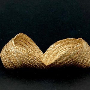 May include: Two woven straw baskets, side by side, against a black background. The baskets are made of light brown straw and have a curved shape. The weave pattern is visible, adding texture to the design.