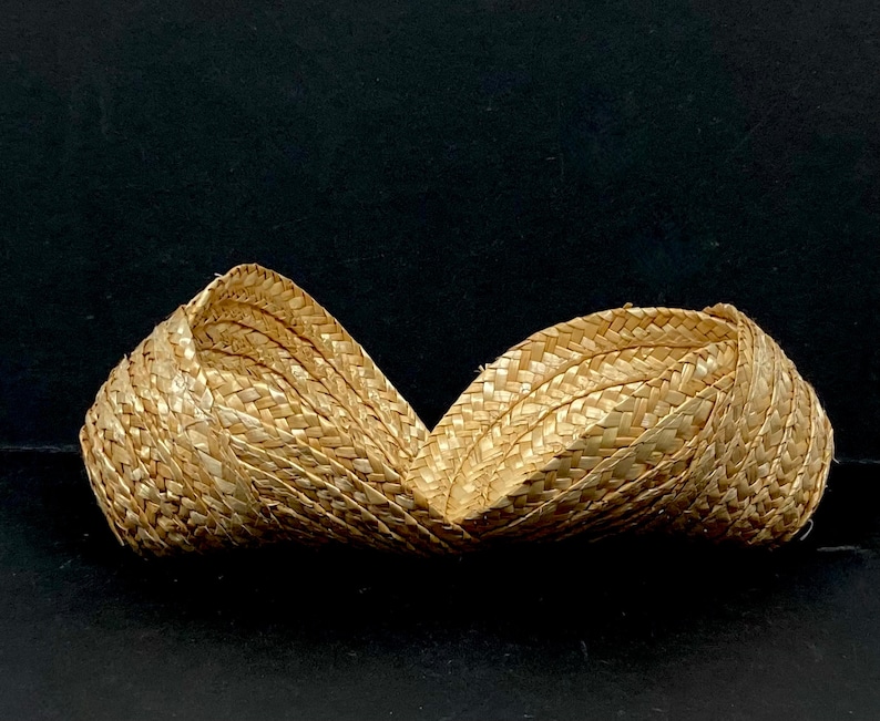 May include: Two woven straw baskets, side by side, against a black background. The baskets are made of light brown straw and have a curved shape. The weave pattern is visible, adding texture to the design.
