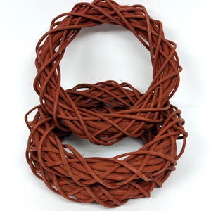 May include: Two brown woven wreaths, one stacked on top of the other, against a white background. The wreaths are made of intertwined, reddish-brown twigs, creating a textured, circular design. The wreaths are suitable for home decor.