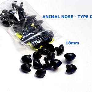May include: A collection of black plastic animal noses, Type D, with a measurement of 18mm. Some noses are in a clear plastic bag, while others are scattered on a white surface. The text "ANIMAL NOSE - TYPE D" is visible.