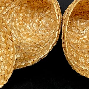 Pu&ograve; includere: Primo piano di tre cappelli di paglia intrecciata. I cappelli sono di colore marrone chiaro e hanno un motivo a trama di cesto. I cappelli sono annidati, con l'interno dei cappelli visibile.