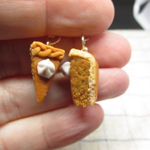 K&ouml;nnte beinhalten: Ein Paar H&auml;ngeohrringe mit Miniatur-K&uuml;rbiskuchenst&uuml;cken. Ein St&uuml;ck hat einen Klecks Schlagsahne oben drauf. Die Ohrringe sind aus Polymer Clay und haben goldfarbene Haken.