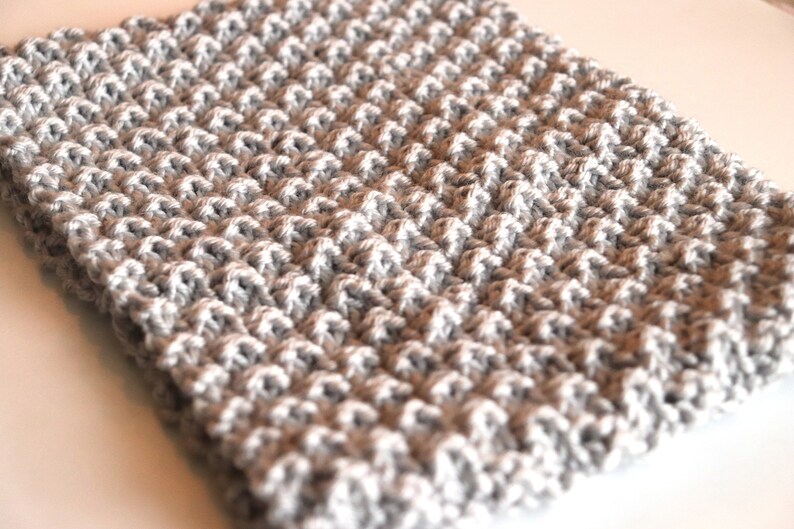 gray knitted seed stitch cowl scarf laying on a table