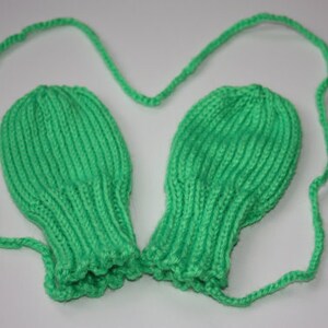 May include: A pair of green knitted fingerless gloves with a matching green string attached.