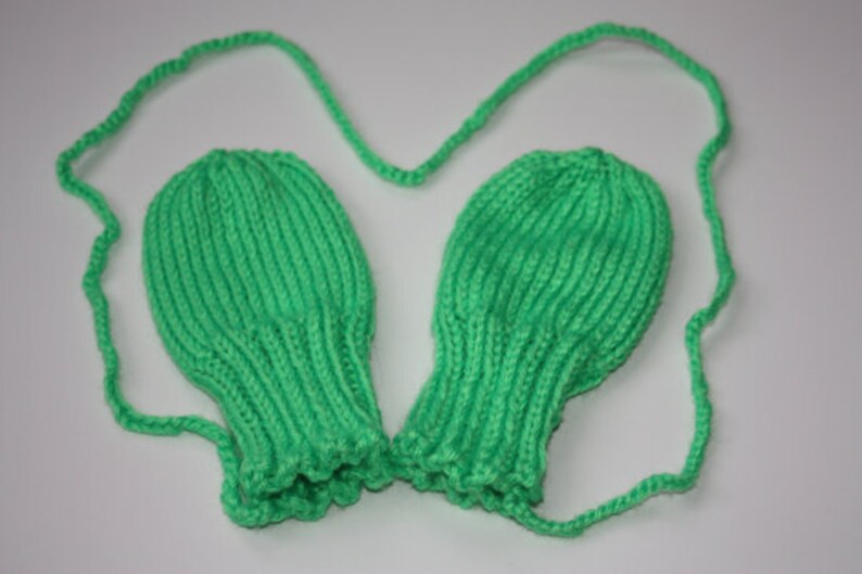 May include: A pair of green knitted fingerless gloves with a matching green string attached.
