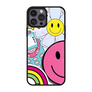 May include: Black phone case with a collage of colorful graphics. The design includes a large pink smiley face, a yellow smiley face in a flower, a rainbow, and a cartoon character. The case has a black border.