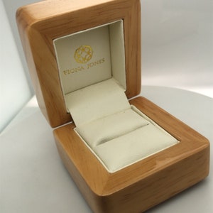 May include: A wooden ring box with a white interior and the text "Fiona Jones" on the lid.