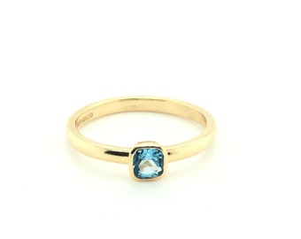 May include: A gold band ring with a square blue topaz gemstone.