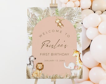 Op de afbeelding: Welkom bij Paislee's eerste verjaardagsschild met een roze achtergrond en illustraties van jungledieren. Het bord staat op een houten ezel.