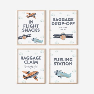 May include: Four printable signs with a blue and white aeroplane theme. The signs read "In Flight Snacks", "Baggage Drop-Off", "Baggage Claim", and "Fueling Station".