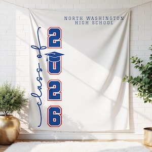 May include: A white banner with the text "North Washington High School" in navy blue. The banner features the words "Class of" in navy blue script, and the numbers "2026" in red with navy blue outlines, along with a graduation cap.