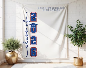 May include: A white banner with the text "North Washington High School" in navy blue. The banner features the words "Class of" in navy blue script, and the numbers "2026" in red with navy blue outlines, along with a graduation cap.