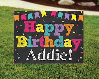 May include: A black chalkboard sign with colorful flags at the top. The sign says "Happy Birthday Addie!" in colorful, handwritten letters.