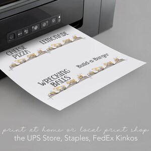 May include: A sheet of paper with a black and white illustration of construction vehicles and the text "Wrecking Balls", "Build-a-Burger", "Lemonade", and "Cheese Pizza". The paper is being printed from a black printer.