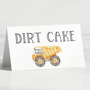 May include: A white card with the text "DIRT CAKE" in black lettering. A yellow toy dump truck with black wheels is pictured below the text.