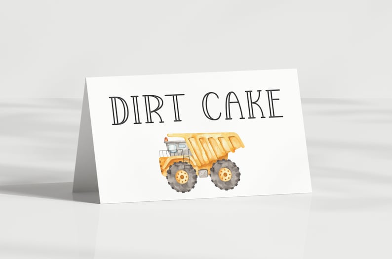 May include: A white card with the text "DIRT CAKE" in black lettering. A yellow toy dump truck with black wheels is pictured below the text.